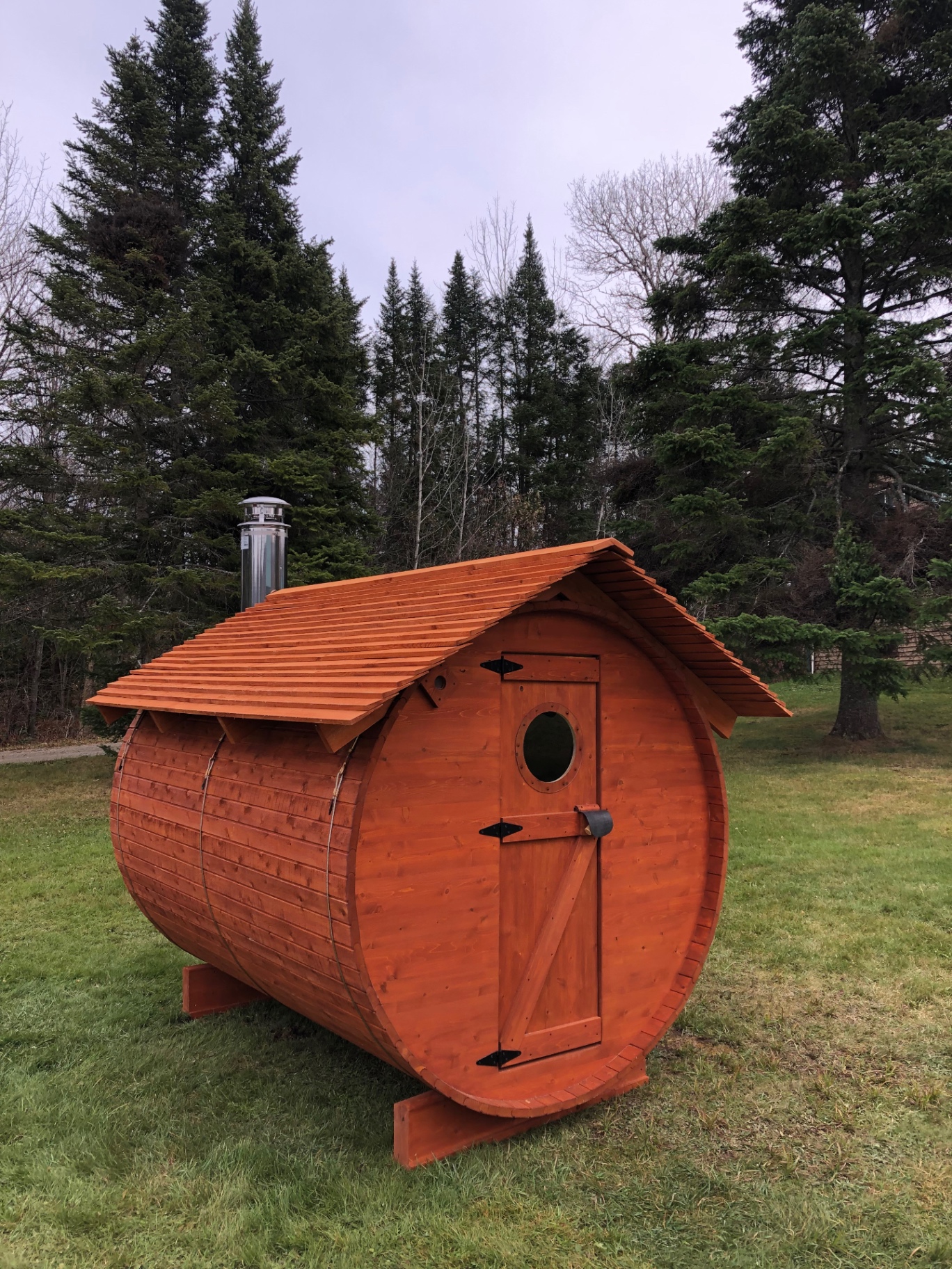 Sauna baril du Québec rouge en cèdre blanc avec toit en bardeaux de cèdre sur pelouse