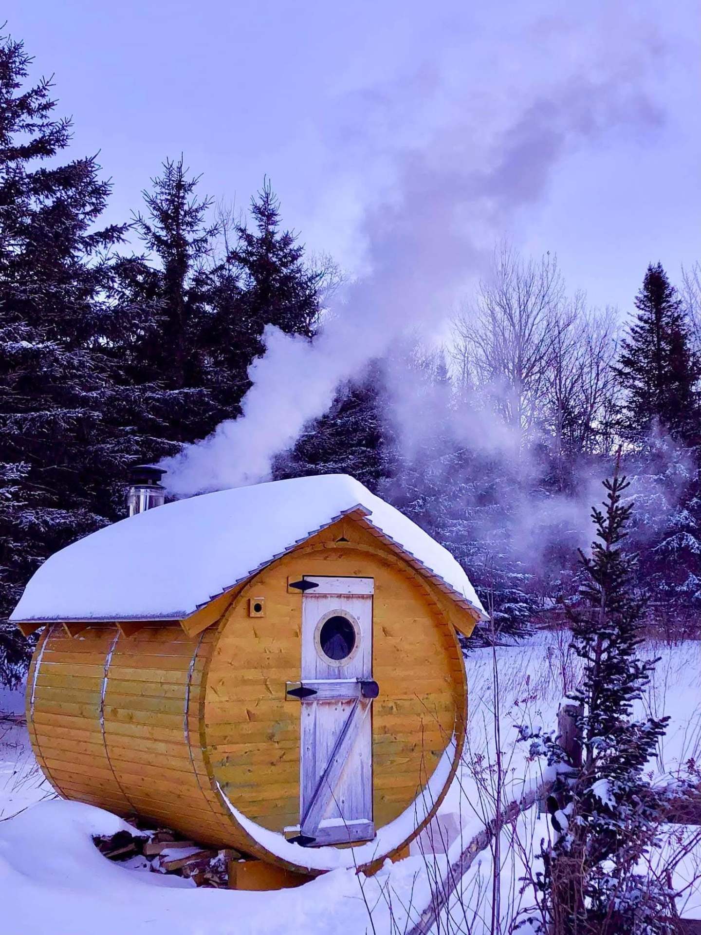 Sauna baril en cèdre blanc du Québec recouvert de neige avec cheminée fumante — Petit Moulin du 4 Milles, Estrie