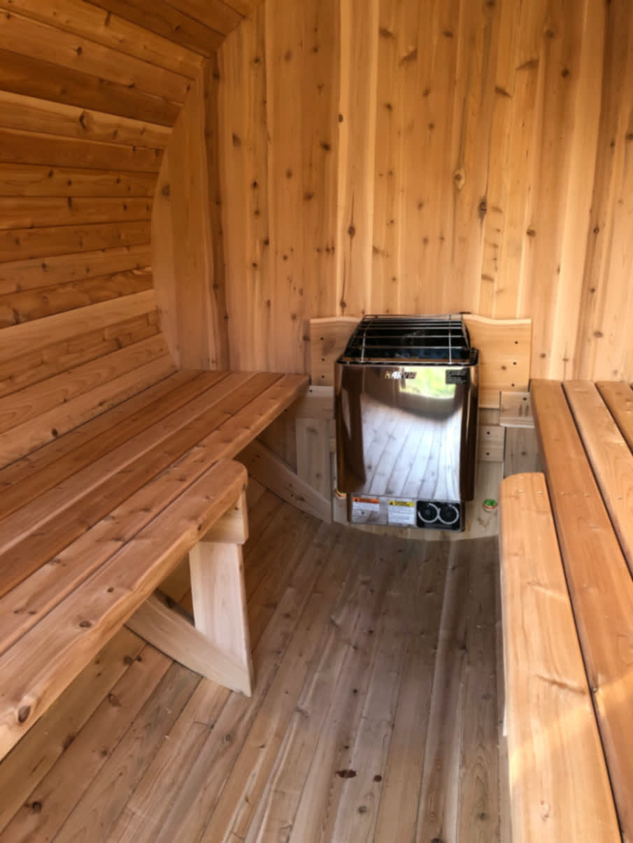 Intérieur d'un sauna baril du Québec en cèdre blanc avec poêle Harvia électrique et bancs d'angle